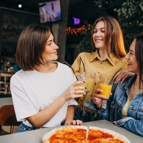 Girls friends having pizza at a bar at a lunch time